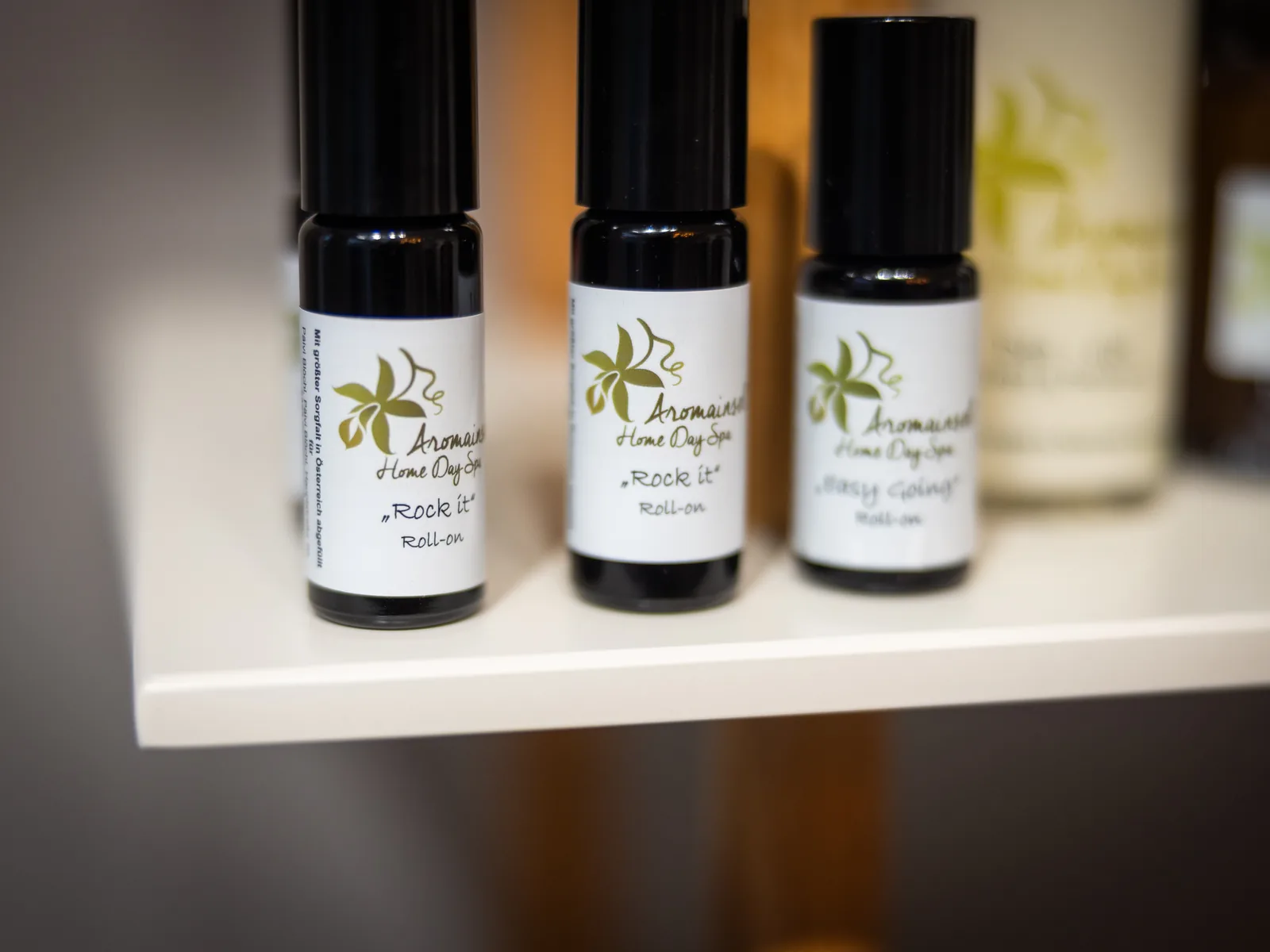 Drei Aromainsel-Roll-ons mit handbeschrifteten Etiketten auf einem Regalbrett